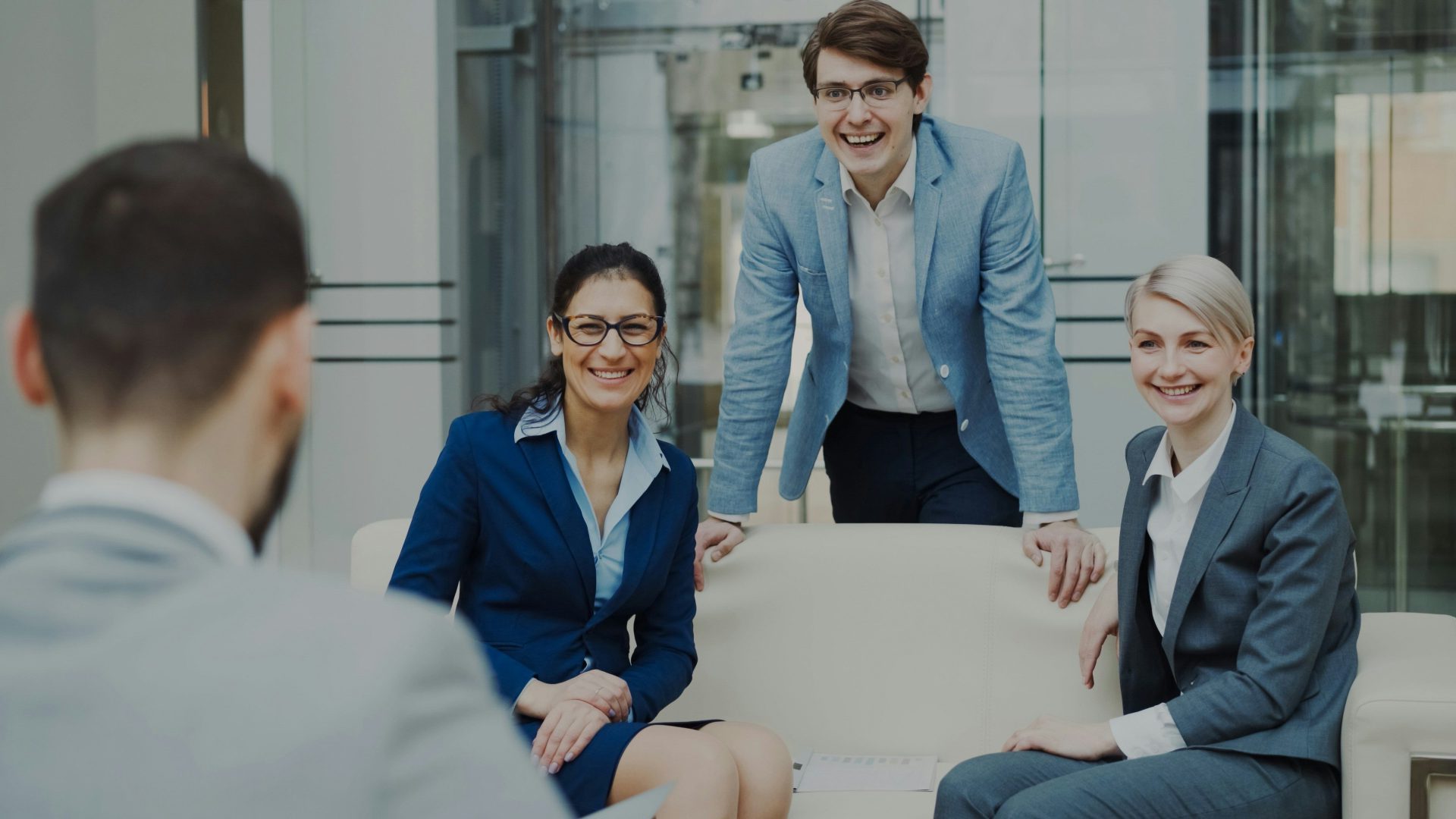 Four smiling business people in a modern office.